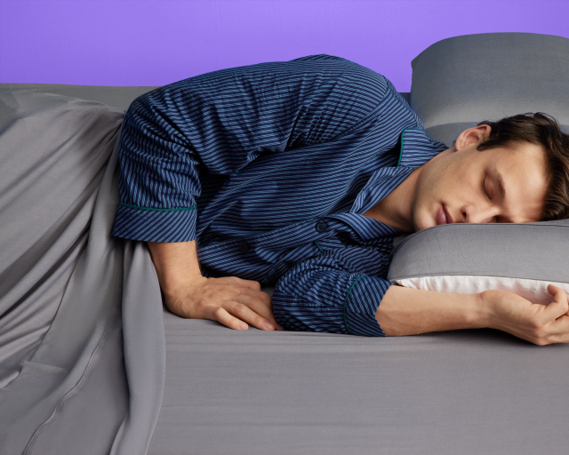 Person sleeping on a Purple mattress and bed frame
