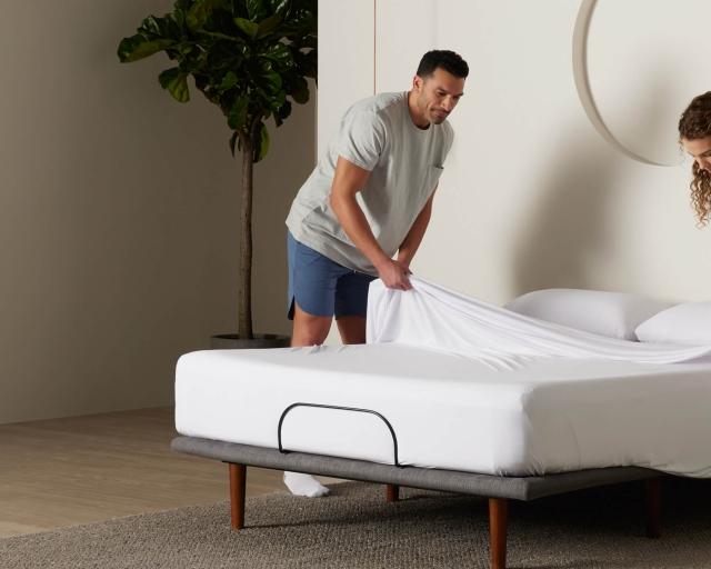 Two people removing a sheet from a Purple mattress.