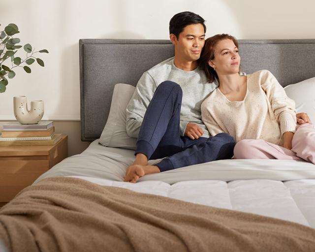 An image showcases a couple lounging on the new blanket they purchased using a blanket size guide.