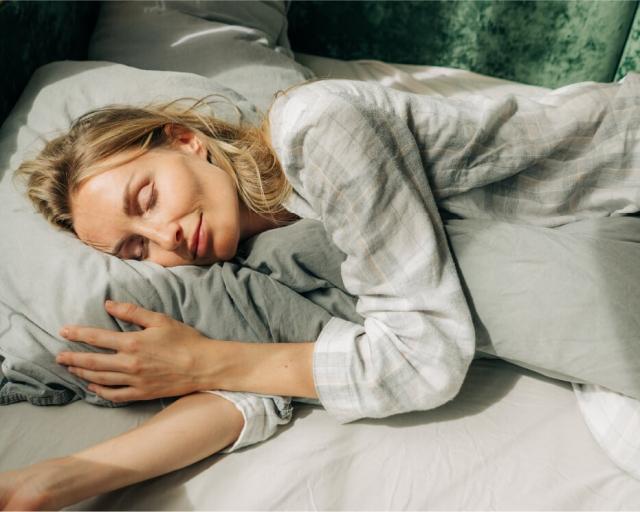 A person sleeping on their side while hugging a pillow to relieve shoulder pain.