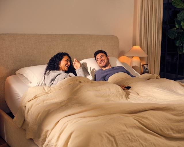 A couple lying on a split king Purple bed.