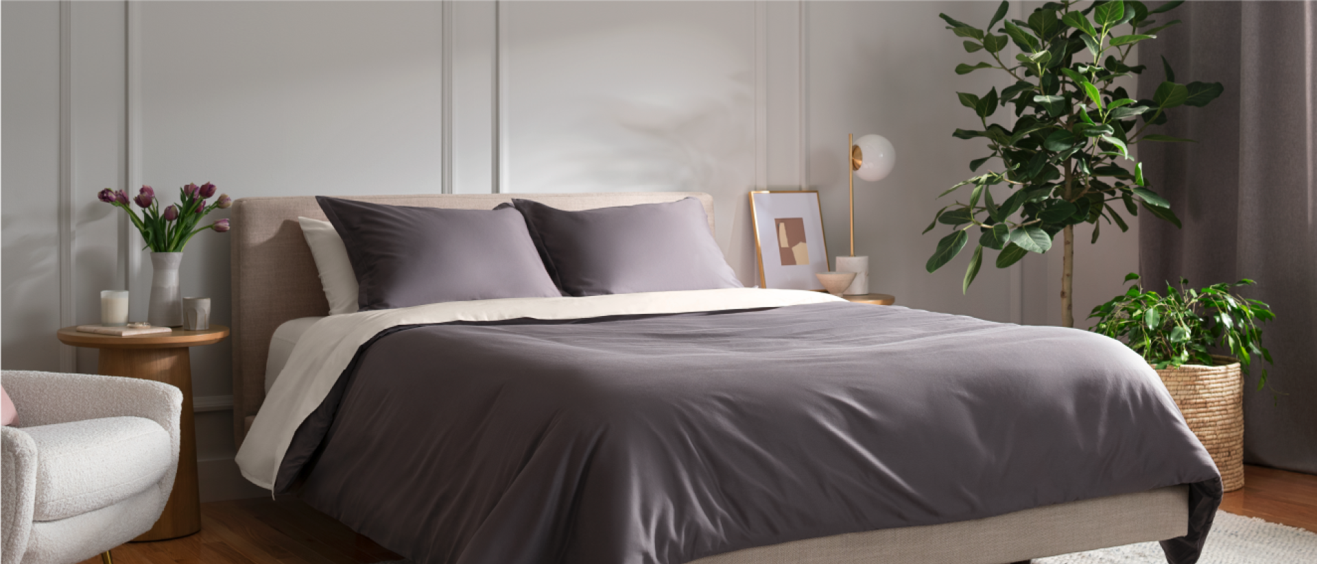 Bedroom with a made bed with grey and white sheets.