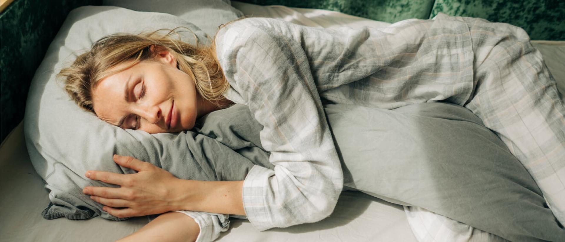 A person sleeping on their side while hugging a pillow to relieve shoulder pain.