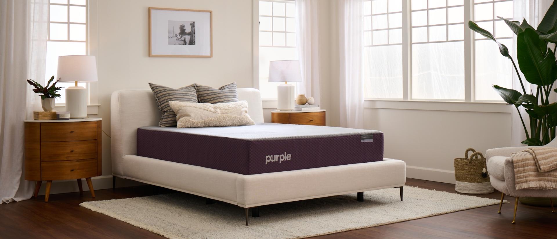 A queen Purple mattress on a cream bed frame in a bright airy bedroom.