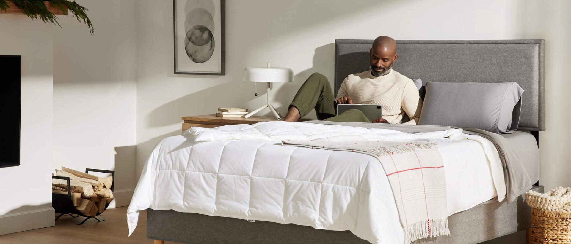 A man lying on a Purple Restore Hybrid mattress reading a book.