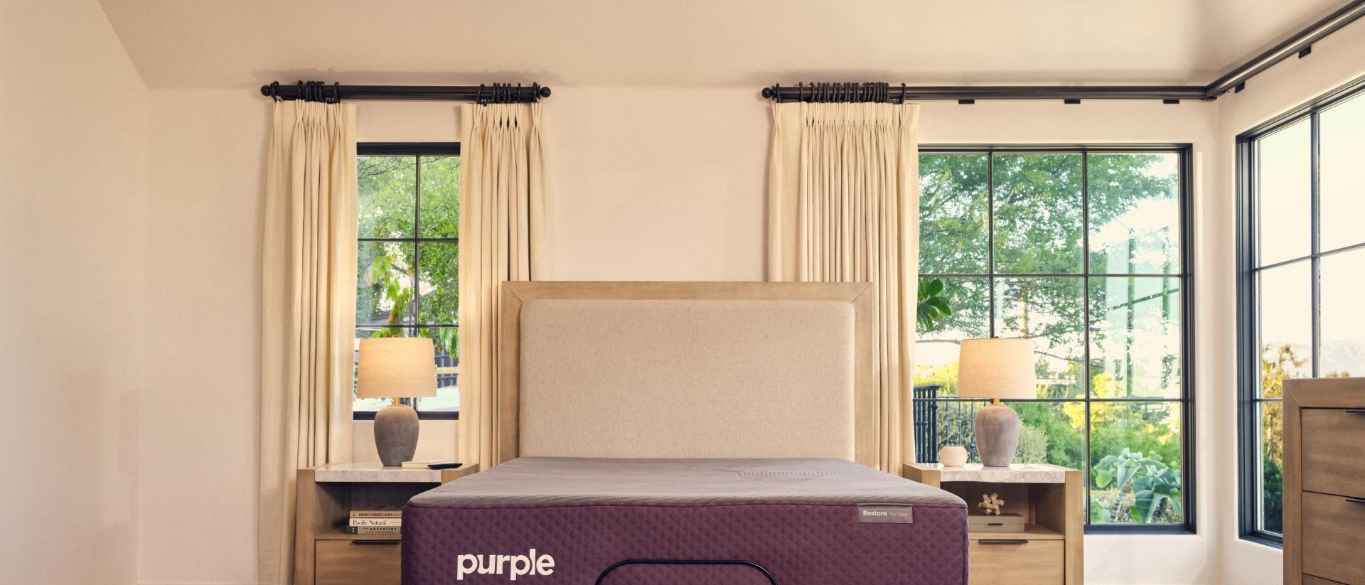 A Purple RestorePremier Hybrid mattress on an upholstered bed frame.