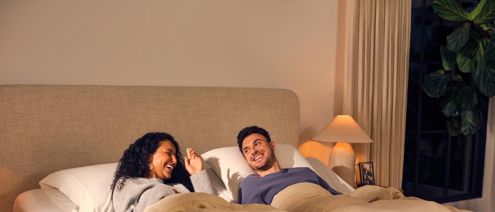 A couple lying on a split king Purple bed.