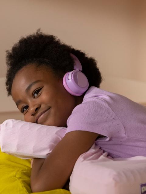 kid hugging kid pillow with headphones on